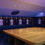 Interior view of Paris Saint-Germain's locker room featuring team jerseys and emblem.