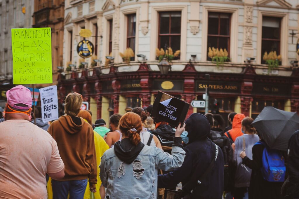 A group of protesters in Manchester advocating for transgender rights with vibrant signs and diverse participants.