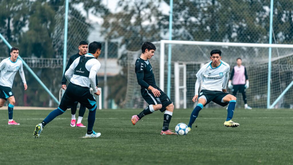 Soccer players engage in a competitive training session on a grassy field outdoors.