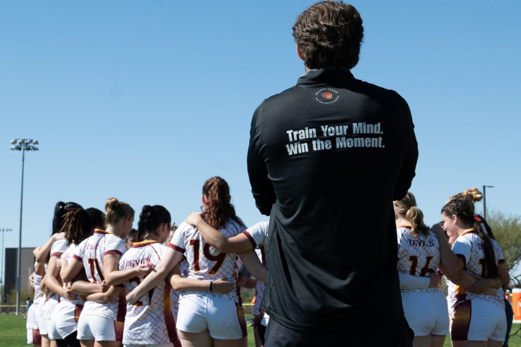 Rugby team huddle during a sunny day game in Tempe, Arizona, focusing on teamwork and strategy.
