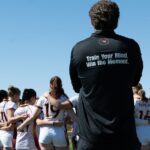 Rugby team huddle during a sunny day game in Tempe, Arizona, focusing on teamwork and strategy.