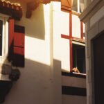 A picturesque view of Basque architecture in Saint-Jean-de-Luz with red shutters and soft sunlight.