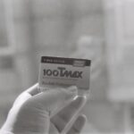 Close-up of Kodak T-Max 100 black and white film held by a hand, showcasing vintage photography equipment.
