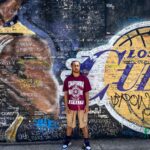 Man stands in front of colorful Los Angeles mural, vibrant street art scene.