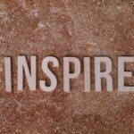 Inspirational word 'INSPIRE' on a textured stone background for motivation.