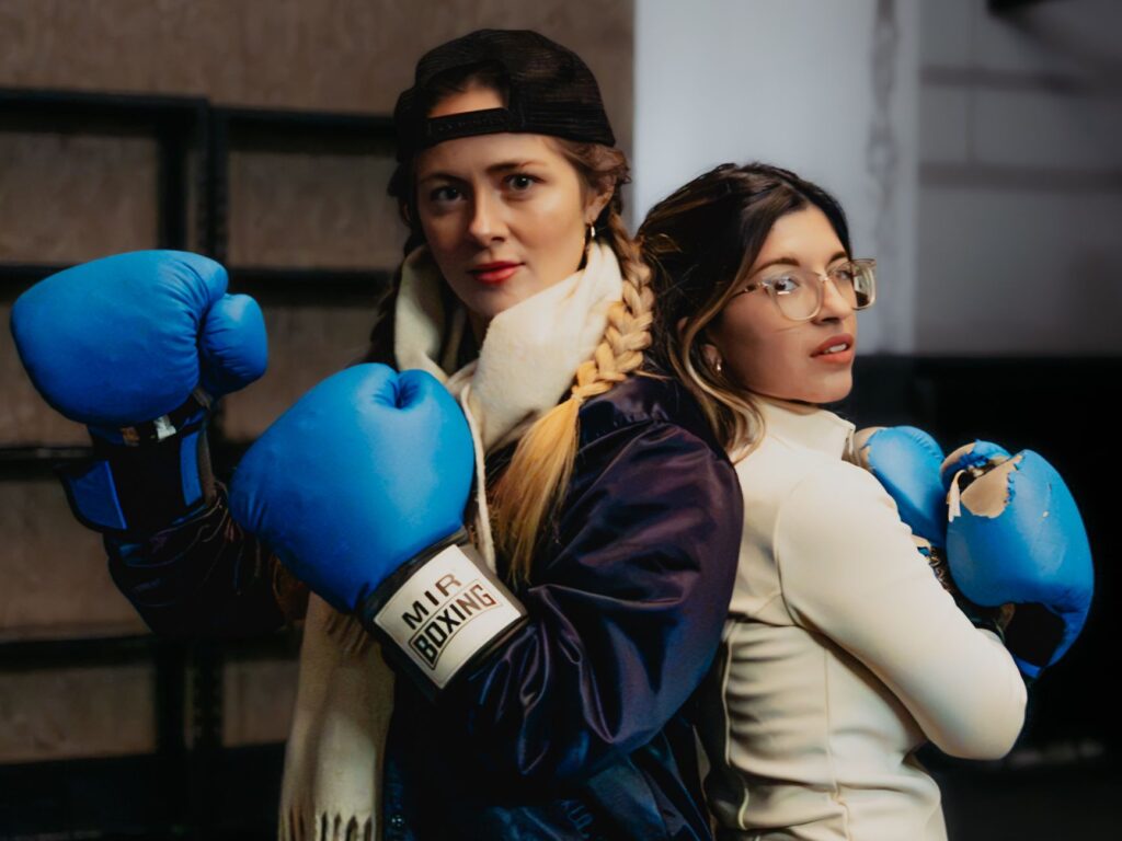 Two women in boxing gloves preparing for training in Buenos Aires. Sports and fitness lifestyle indoors.