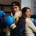 Two women in boxing gloves preparing for training in Buenos Aires. Sports and fitness lifestyle indoors.