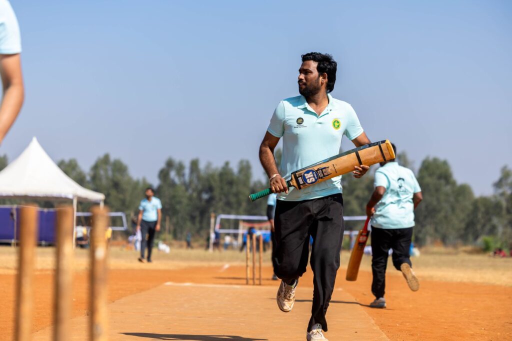 Cricketer with bat ready on sunny day outdoor field, sporting event.