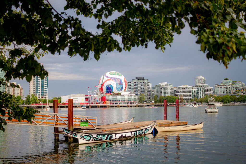 Colorful view of Vancouver's waterfront with boats, cityscape, and iconic architecture.