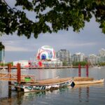 Colorful view of Vancouver's waterfront with boats, cityscape, and iconic architecture.
