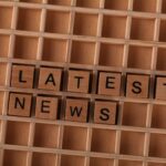 Wooden letter blocks spelling Latest News on a grid background, ideal for media themes.