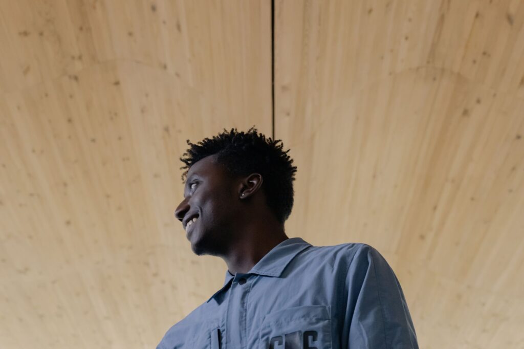 Portrait of a smiling young man in a blue shirt looking away, captured indoors.