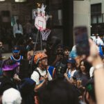 Vibrant street scene of basketball fans wearing jerseys and celebrating with a mini hoop setup.