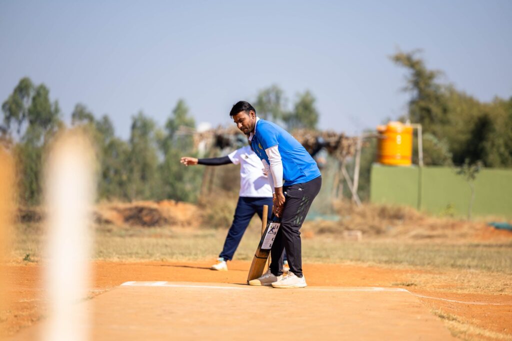 Two men playing cricket outdoors on a sunny day, focusing on the batsman preparing to hit.
