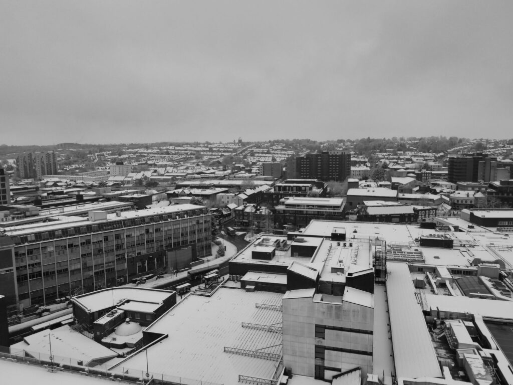 Black and white aerial view of Luton city covered in snow during winter, showcasing urban architecture.