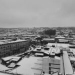 Black and white aerial view of Luton city covered in snow during winter, showcasing urban architecture.