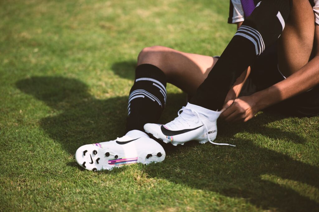 Close-up of a soccer player tying cleats on a sunny grass field, ready for action.