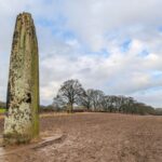 Neolithic standing stones in a rural field in Boroughbridge, England under a cloudy winter sky.