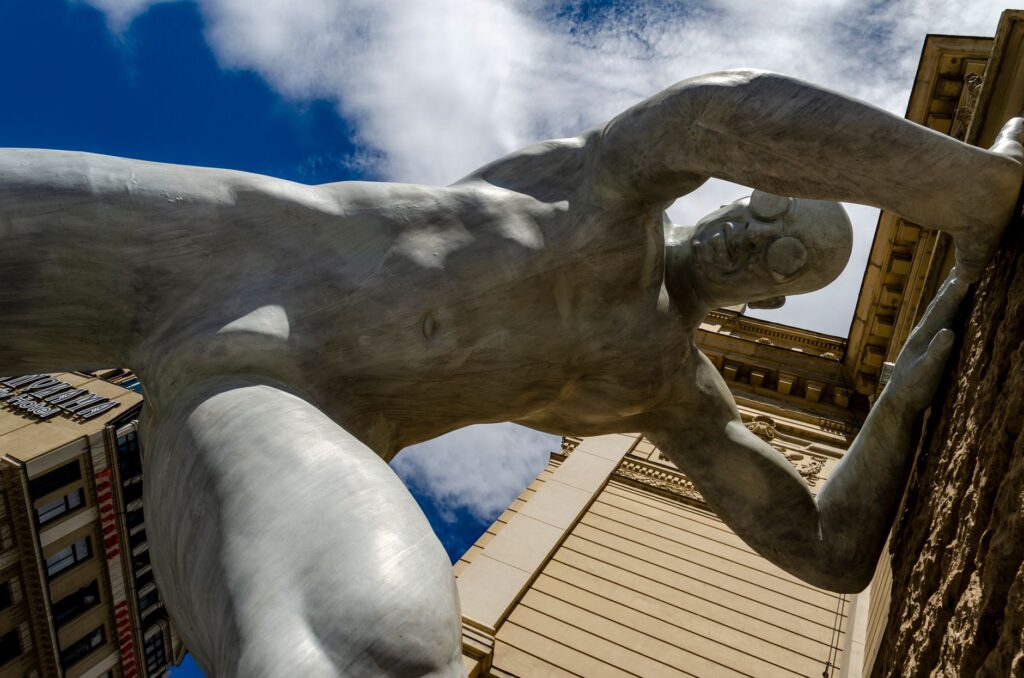 Imposing sculpture reaching out from a building in Lviv, Ukraine, under a vivid sky.