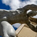 Imposing sculpture reaching out from a building in Lviv, Ukraine, under a vivid sky.