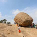 Tourists gather around the iconic Krishna's Butter Ball in Mahabalipuram, India, a popular travel attraction.