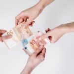 Two pairs of hands exchanging Euro banknotes, symbolizing finance and transaction.