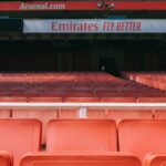 Empty red seats at Arsenal's Emirates Stadium in London, showcasing its vibrant atmosphere.