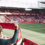 Passionate soccer supporters with scarves in Anfield Stadium, capturing the thrill of the game.
