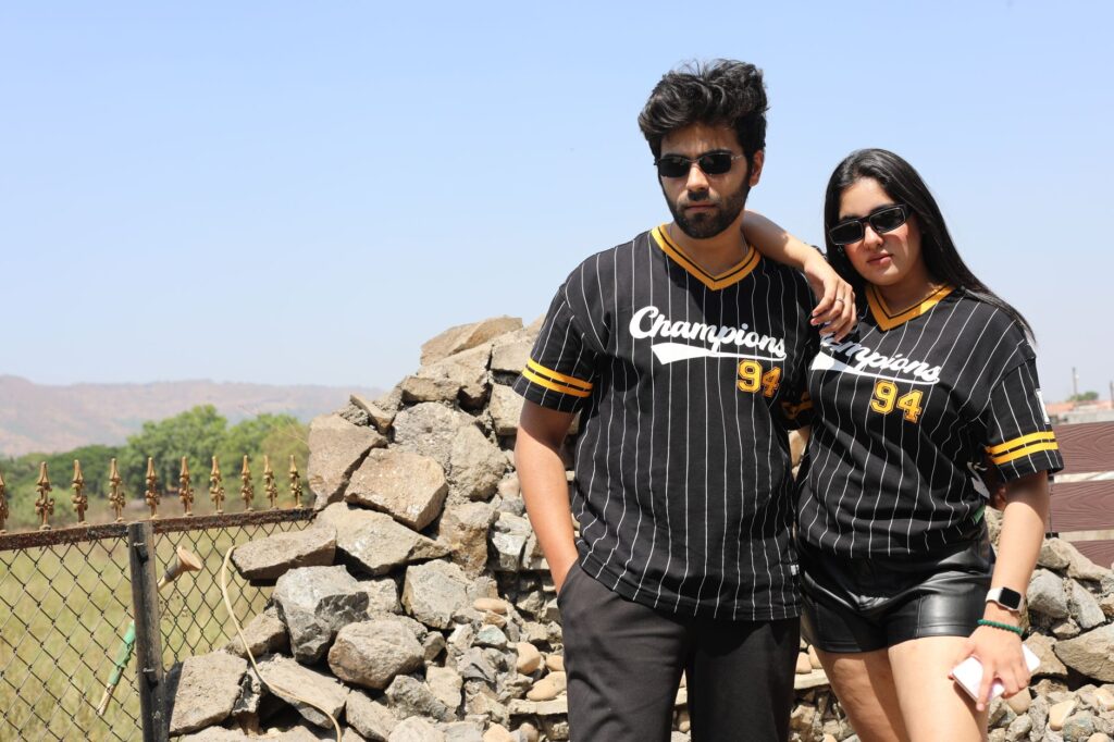Outdoor portrait of two stylish adults wearing matching jerseys on a sunny day.
