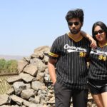 Outdoor portrait of two stylish adults wearing matching jerseys on a sunny day.
