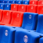Rows of red and blue stadium seats featuring Paris emblems, vibrant and empty.