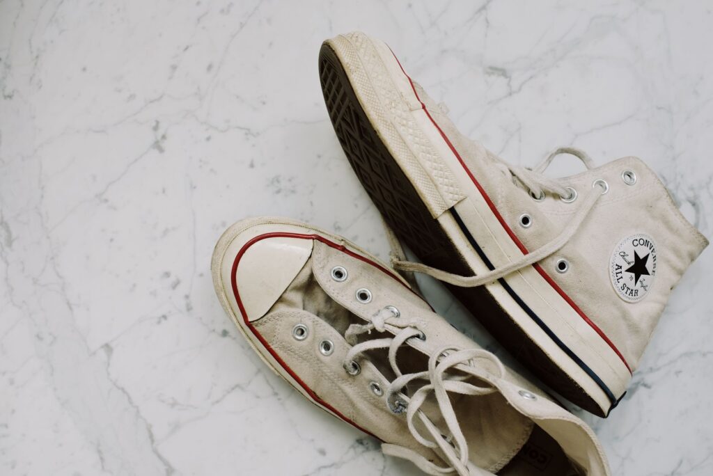 Close-up of worn Converse All-Star sneakers on a marble floor for a vintage fashion style.