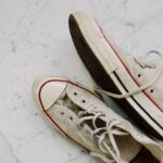 Close-up of worn Converse All-Star sneakers on a marble floor for a vintage fashion style.