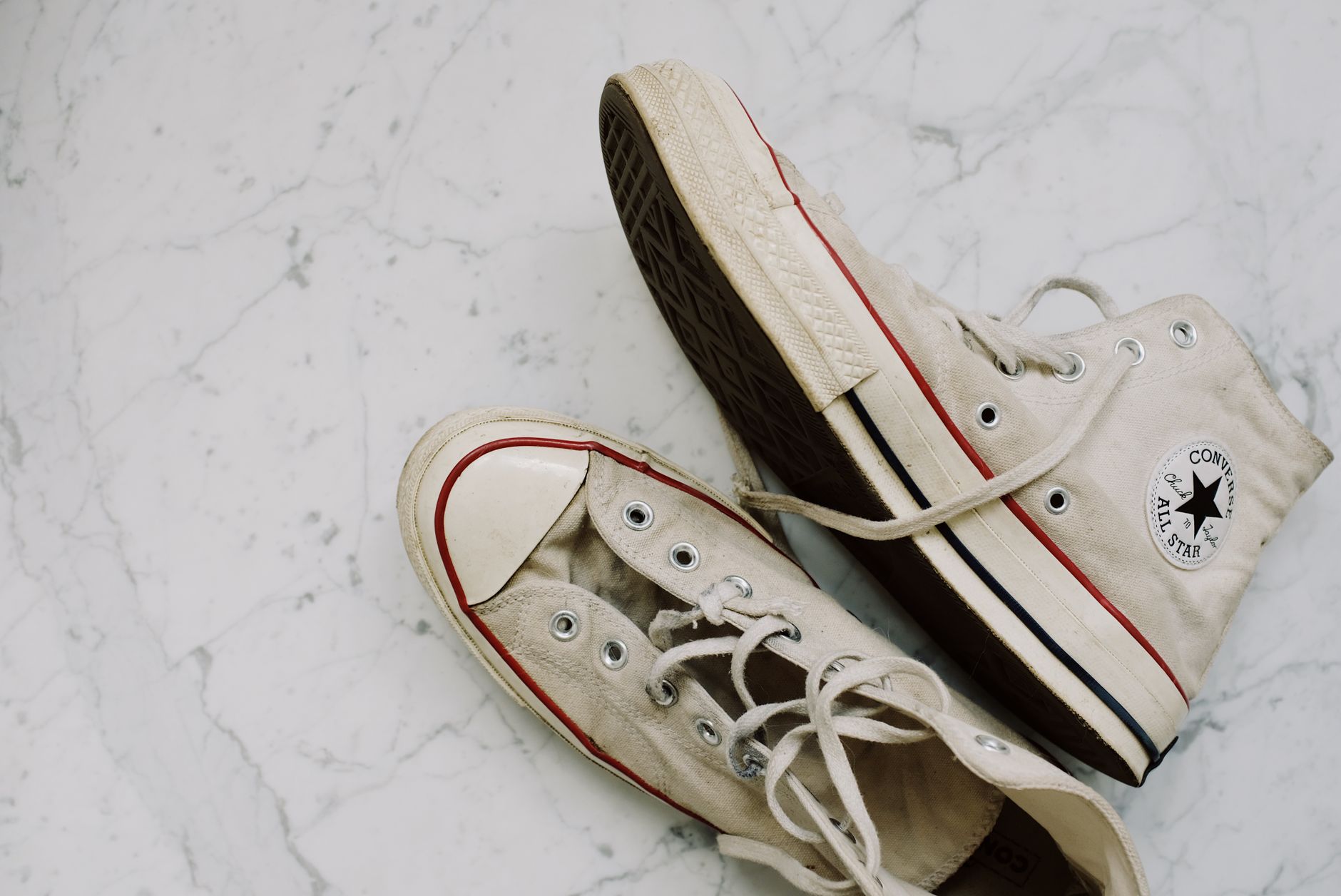 Close-up of worn Converse All-Star sneakers on a marble floor for a vintage fashion style.