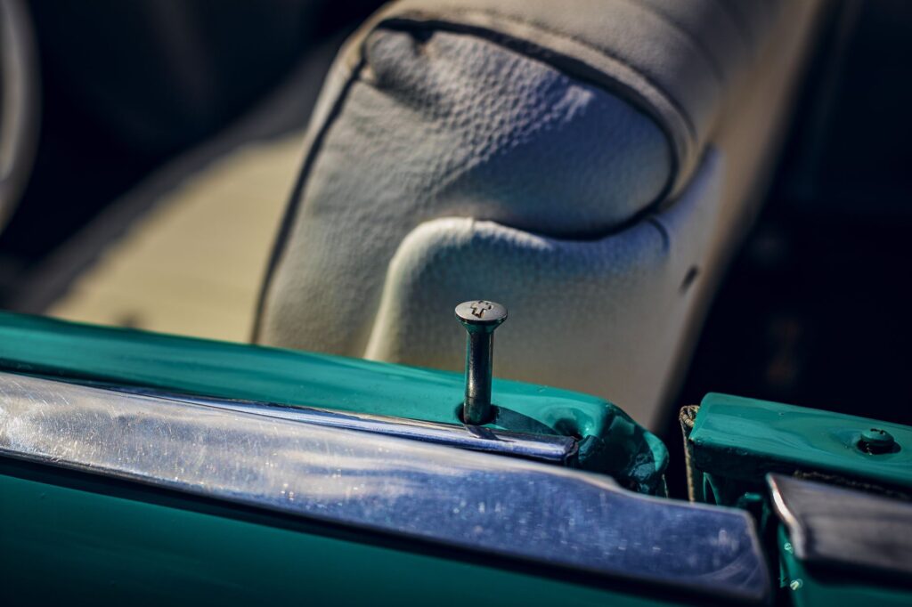 Close-up of a vintage car interior focusing on chrome trim and teal door detail.