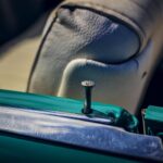 Close-up of a vintage car interior focusing on chrome trim and teal door detail.