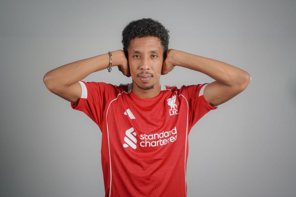 Portrait of a man wearing a red soccer jersey with a confident expression indoors.