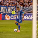 A soccer player in blue dribbles the ball during an outdoor football match.
