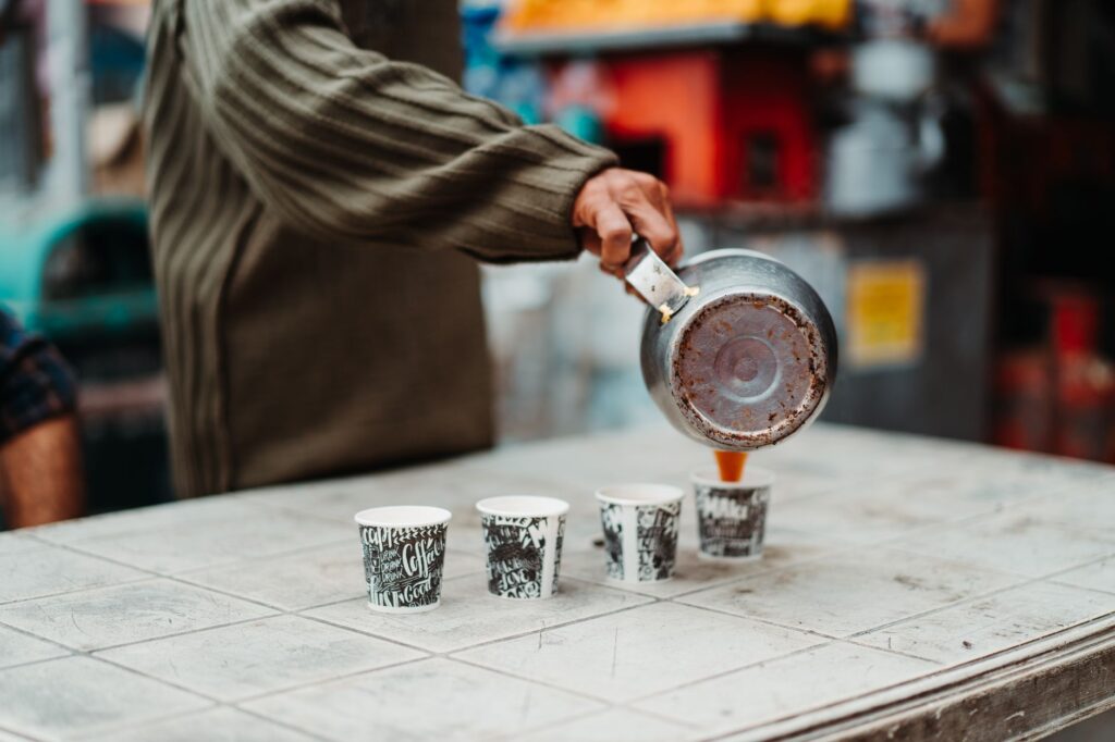 Street vendor pours coffee into cups on a table, capturing urban lifestyle.