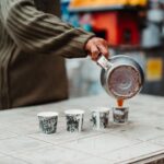 Street vendor pours coffee into cups on a table, capturing urban lifestyle.