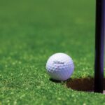 Close-up of a golf ball near a hole on a vibrant golf green, capturing the moment of near success.