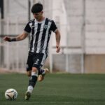 A young soccer player in action, dribbling the ball during a game on the field.