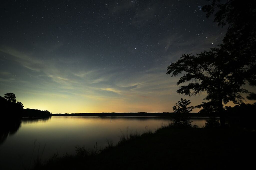 Star-filled night sky reflected on a tranquil lake in Elberton, Georgia.