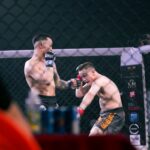 Two MMA fighters engaging in a fierce match inside a caged octagon ring, showcasing martial arts skills.