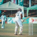 Cricketer in uniform ready to bat on a sunny day. Outdoor sports scene.