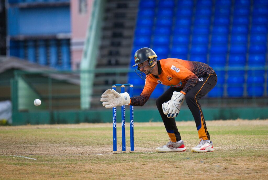 Focused wicketkeeper on cricket field in Basseterre, Saint Kitts and Nevis, during a daytime match.