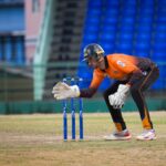 Focused wicketkeeper on cricket field in Basseterre, Saint Kitts and Nevis, during a daytime match.