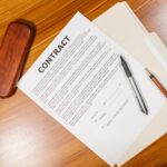 High-angle view of a contract document with pens and a case on a wooden table.