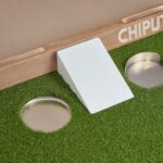 Enhance your golf skills with this innovative chip and putt training aid featuring artificial turf and multiple practice holes.