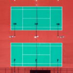 Bright aerial shot of two tennis courts on a sunny day.
